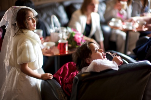Sisters in wedding dresses watch the wedding on a TV inside the pub
