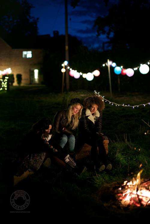 Models (L-R) Lizzie Bowden, Sophie Harries and Leanne Pollock relax by a bonfire. New Look behind the scenes shoot of their Autumn / Winter 2013 collection advertising film by Cherry Duck. Walnuts Farm, Old Heathfield, East Sussex, UK. August 22, 2013. Photo: ©Edmond Terakopian
